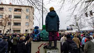 Lapsia sähkökaapin päällä. Ympärillä hyvin paljon ihmisiä.