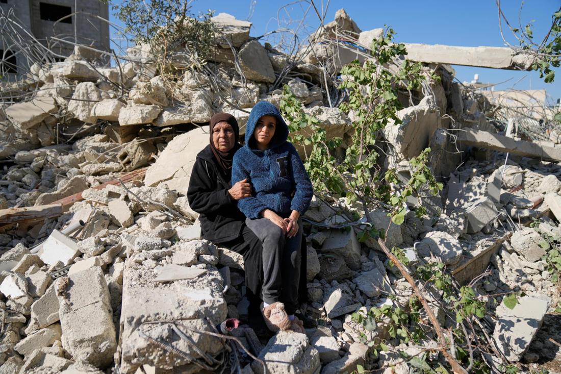 Frauen sitzen auf Gebäudetrümmern.