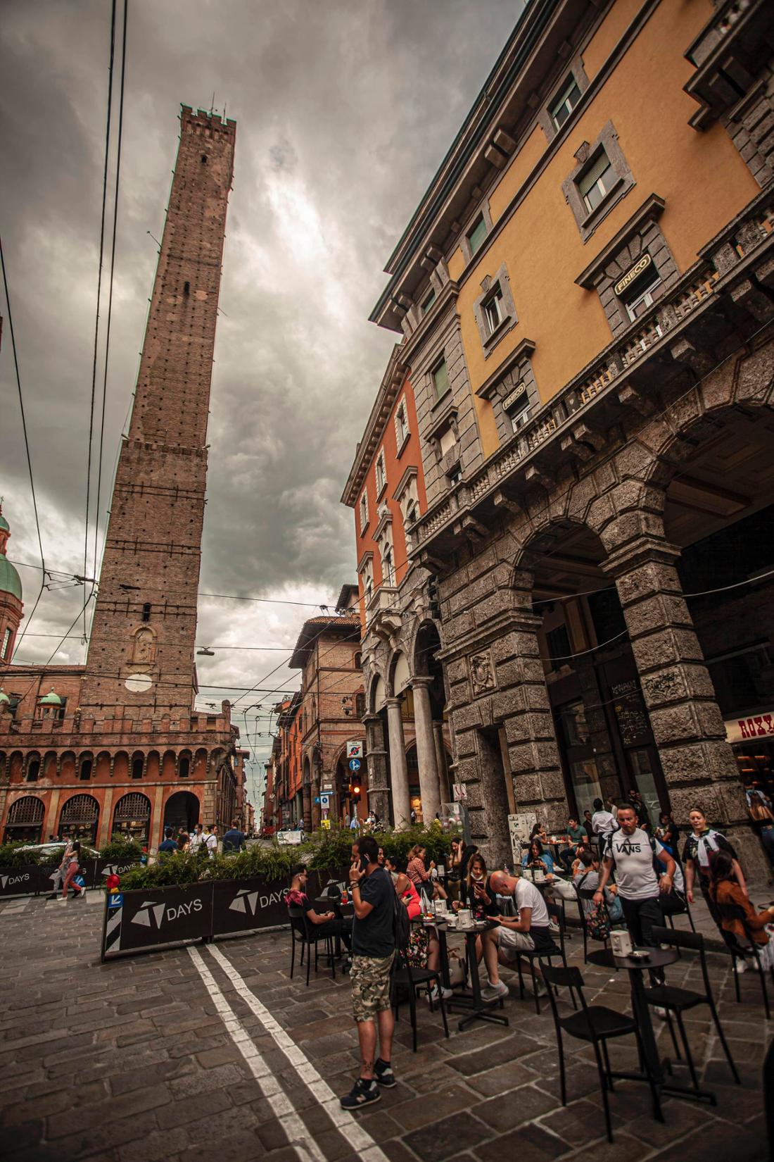 Menschen genießen ein Essen im Freien in der Nähe des Asinelli-Turms in Bologna.