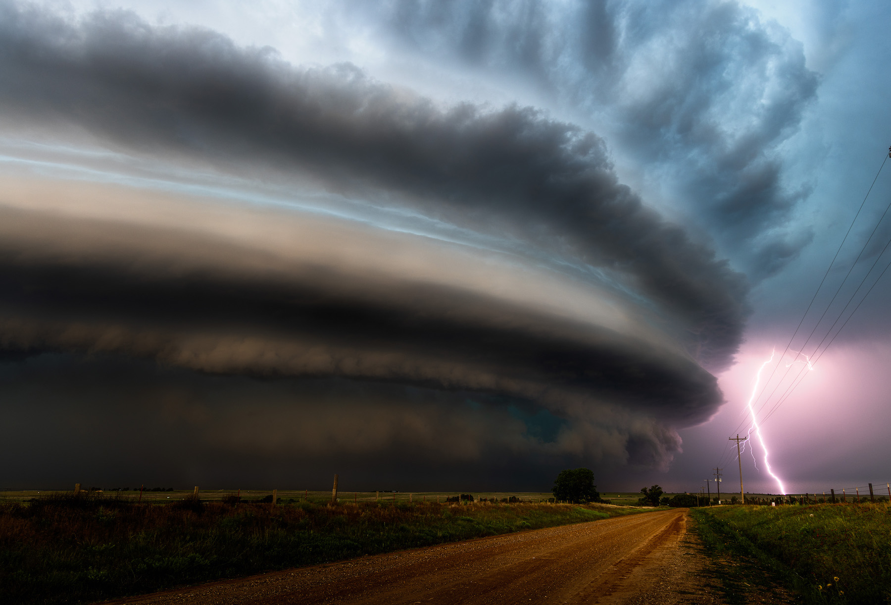 large storm cell moves over rural area with a lightning strike