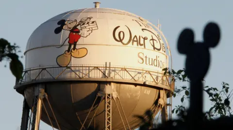 Reuters The water tower at The Walt Disney Co., featuring the character Mickey Mouse, is seen behind a silhouette of mouse ears on the fencing surrounding the company's headquarters.