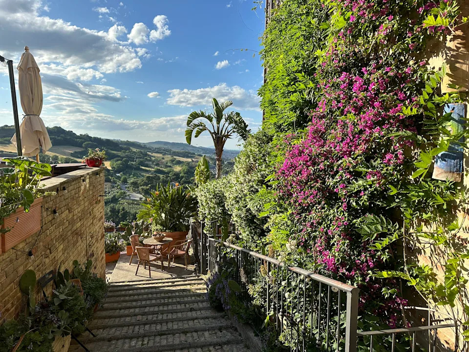 Flower-lined walkway looking out on the hills of Torre di Palme, Italy