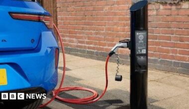 A blue electric car being charged at a point.