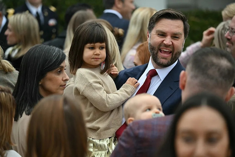 jd vance holds his daughter among a crowd of people