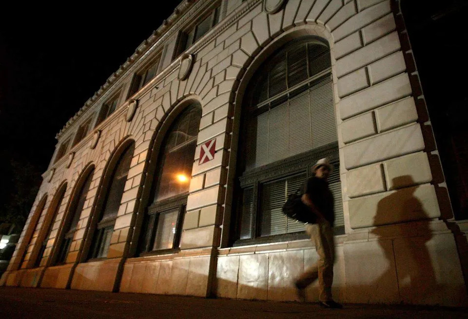 A pedestrian passes by the classic architecture of the closed Bank of Italy building bathed in light from a Grizzlies game on the night on May 7, 2011.