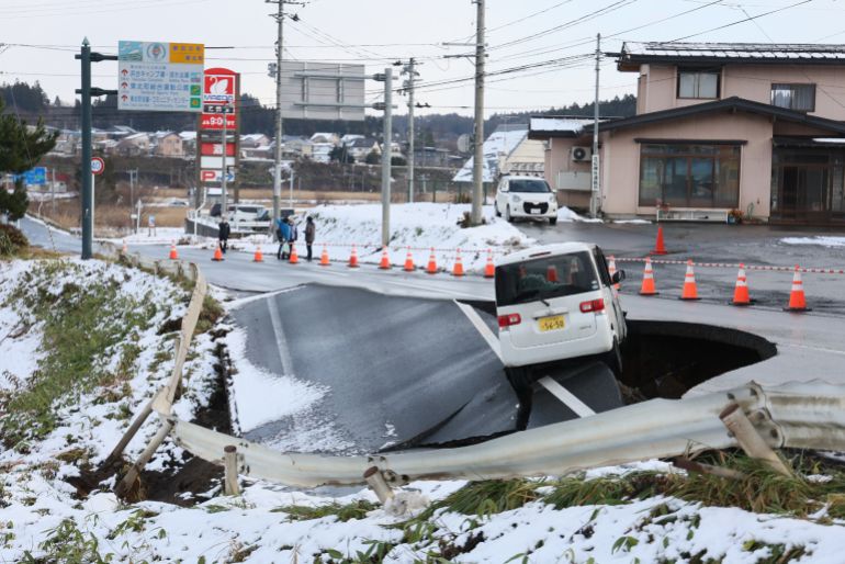 A vehicle rests on the edge of a collapsed road in Tohoku town in Aomori Prefecture on December 9, 2025, following a 7.5 magnitude earthquake off northern Japan. A big quake off northern Japan left at least 30 injured, authorities said on December 9, damaging roads and leaving thousands without power in freezing temperatures. (Photo by JIJI Press / AFP) / Japan OUT / JAPAN OUT / JAPAN OUT