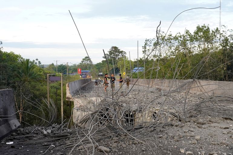 People stand on a damaged bridge in Pursat in Pursat province on December 13, 2025, amid clashes along the Cambodia-Thailand border. The latest clashes between the Southeast Asian neighbours, which stem from a long-running dispute over the colonial-era demarcation of their 800-kilometre (500-mile) frontier, have displaced around half a million on both sides. (Photo by AFP)