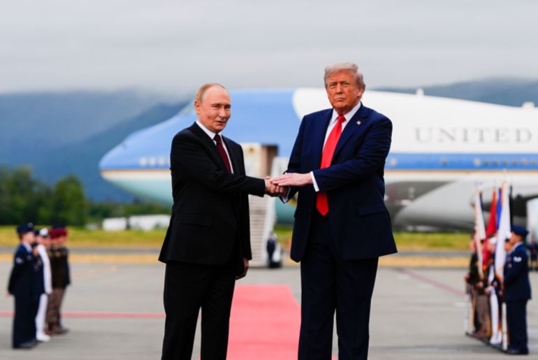 Trump and Putin shake hands on a red carpet leading from Air Force One.