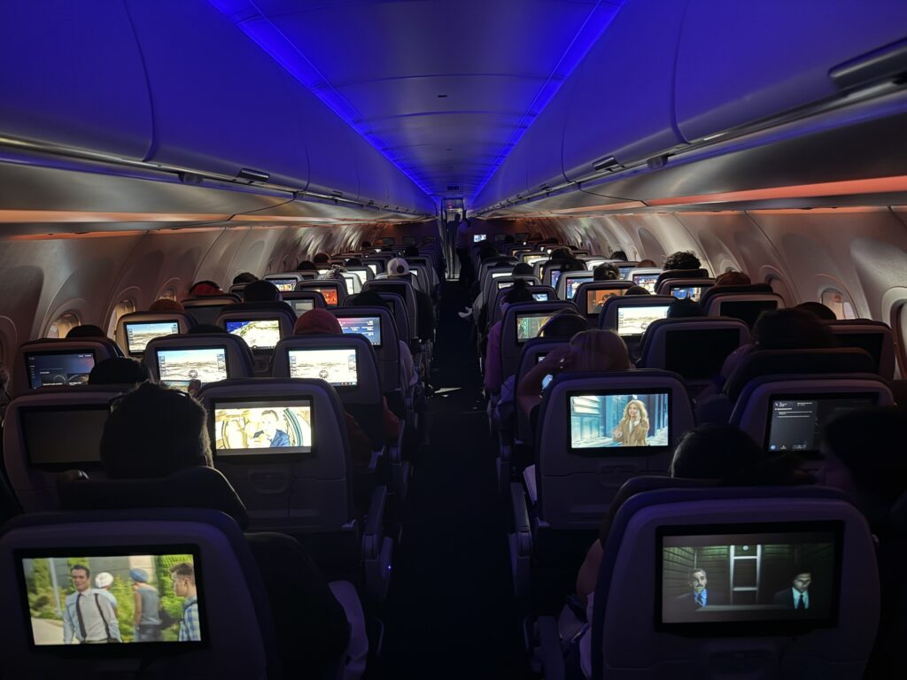 Photo from the rear of the aircraft looking forward at the economy class cabin, with lots of seatback IFE screens in use.