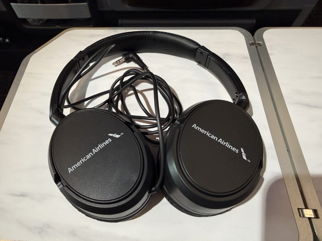 American Airlines headphones are resting on the tray table. 