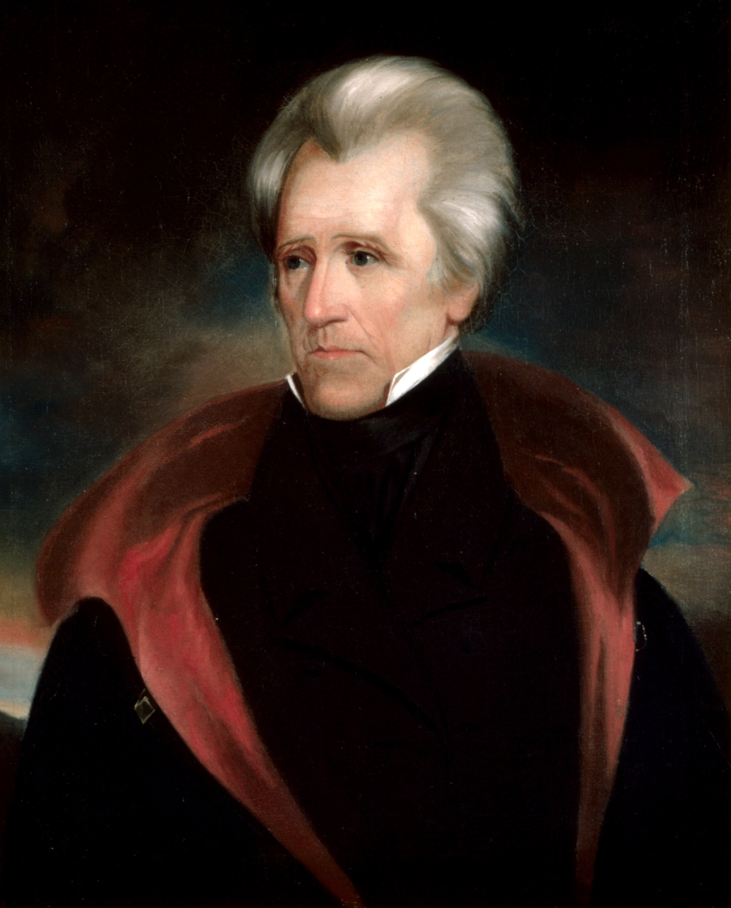 A cropped portrait painting of Andrew Jackson, the seventh President of the United States. He is shown from the chest up, facing slightly to the left, with a serious expression. He has white or silvery hair, a high white collar, and is wearing a dark coat with a wide, reddish-brown collar or cloak draped over his shoulders. The background is dark and indistinct.