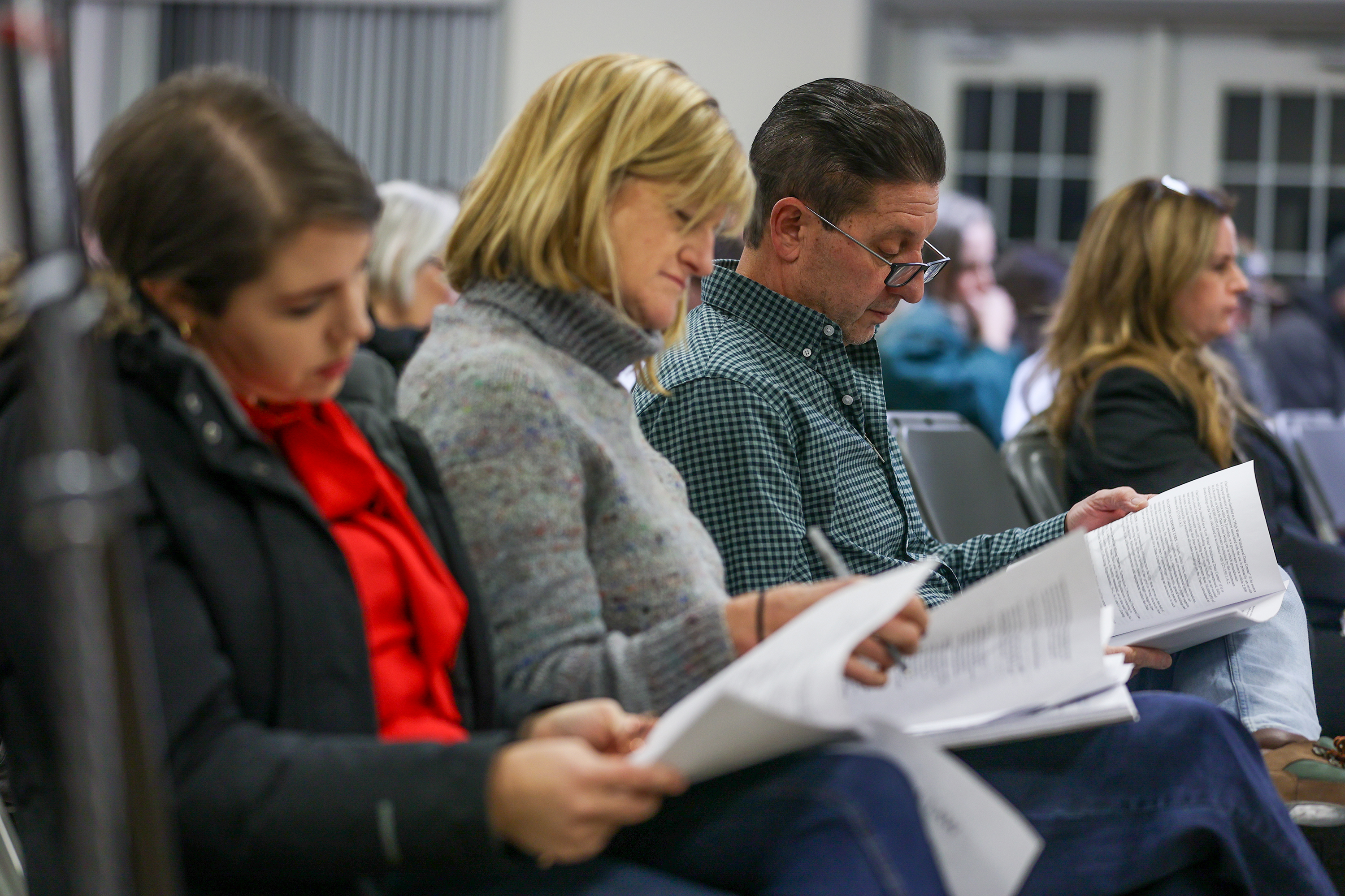 Attendees read through the agenda during a public hearing regarding...