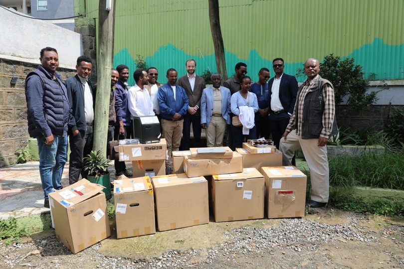 A group of people stand outdoors behind a collection of boxed equipment, including laptops and printers, being handed over to the Refugees and Returnees Service as part of the programme’s support in Ethiopia.