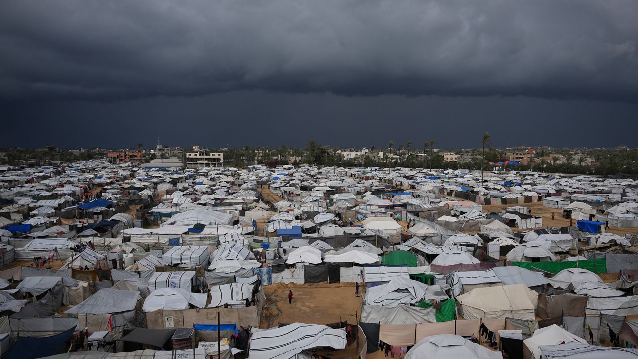 Palestinian children stand on an area surrounded by makeshift tents in a camp for displaced people in Deir al-Balah, central Gaza Strip, Saturday, Dec. 27, 2025. (AP Photo/Abdel Kareem Hana)