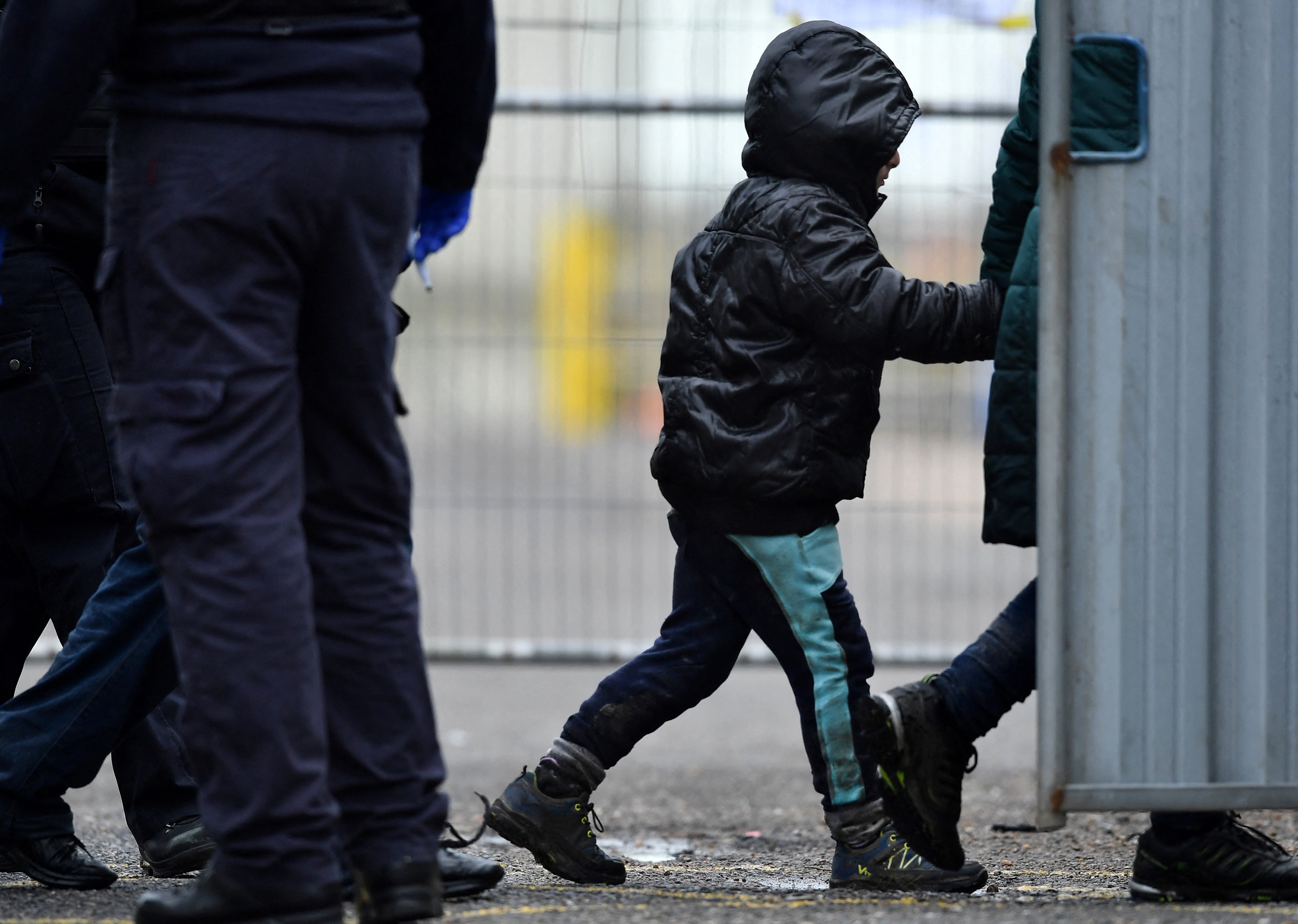 A UK Immigration Enforcement officer escorts a child migrant, picked up at sea attempting to cross the English Channel, on arrival at the Marina in Dover, southeast England, on January 10, 2022