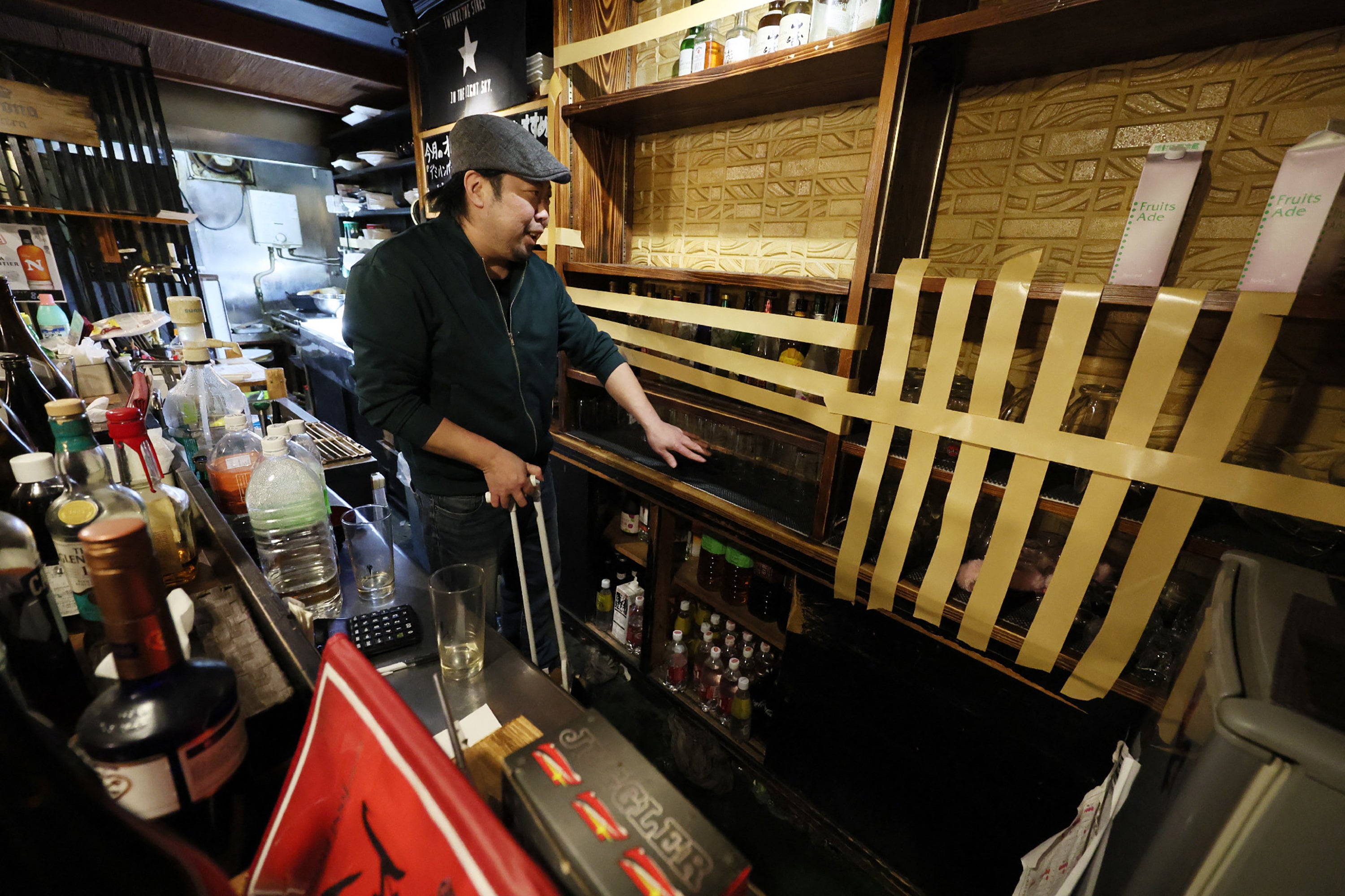 An employee uses adhesive tape to reinforce bottles and glasses to prevent them from falling at a pub