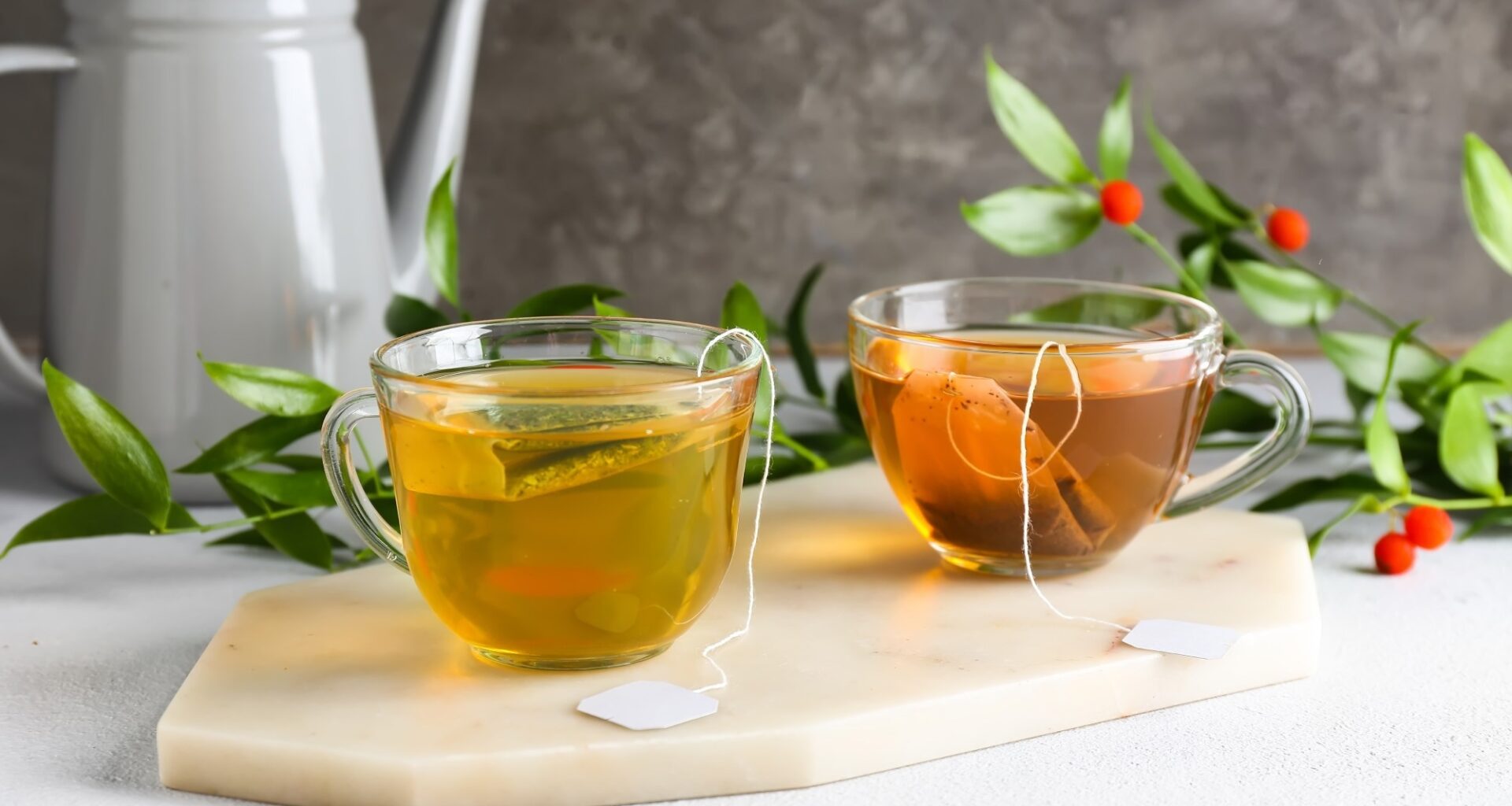 Cups of aromatic green and black tea on light background