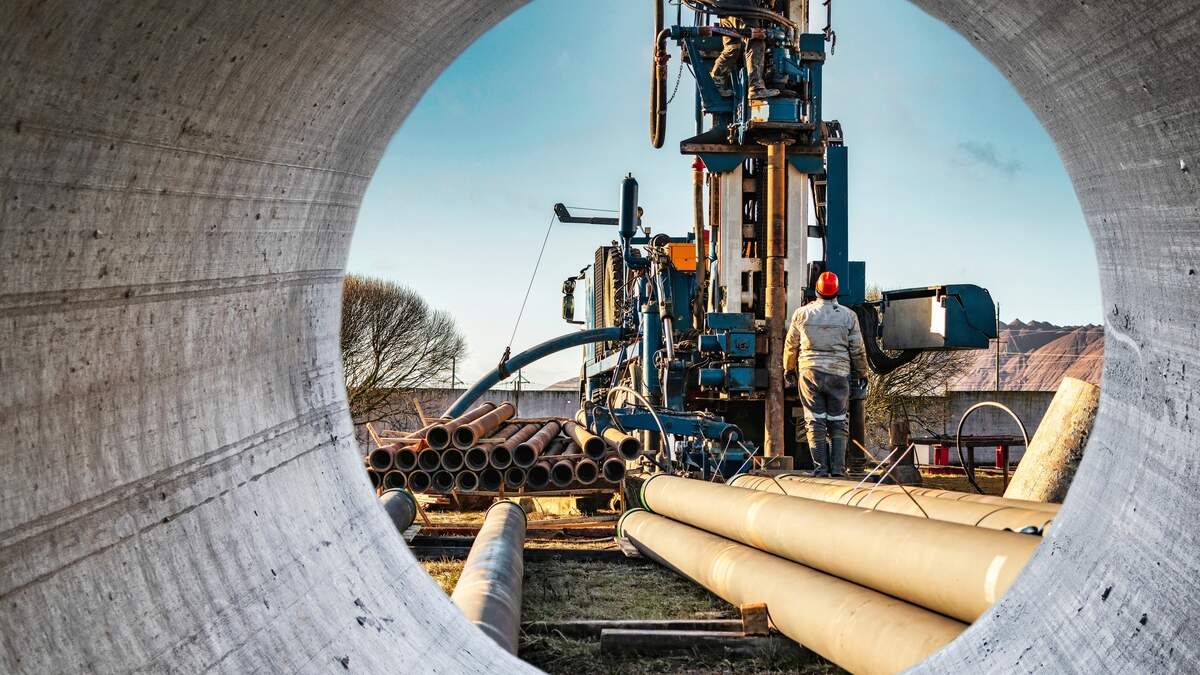 Metal tubes stacked near an oil and gas drilling platform.