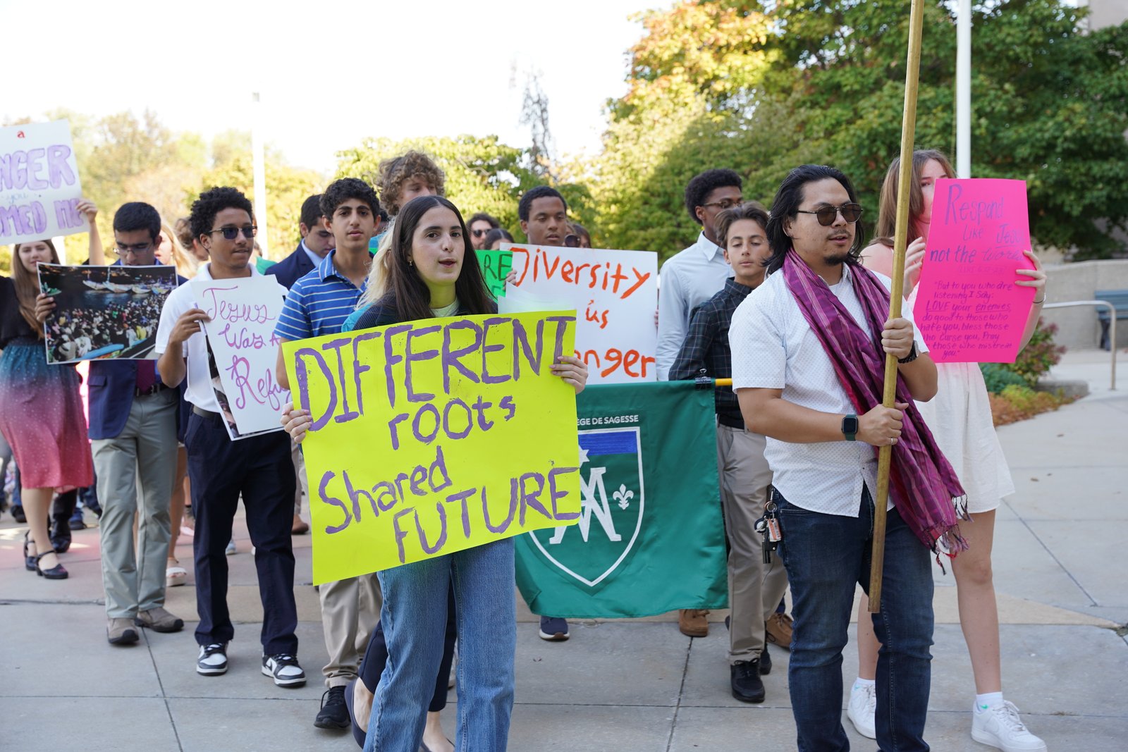 Members of Strangers No Longer process around the campus of the Cathedral of the Most Blessed Sacrament in Detroit before Mass for the World Day of Migrants and Refugees in October, carrying signs in support of immigration rights. (Photo by Daniel Meloy | Detroit Catholic)