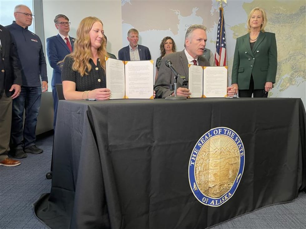 Governor Mike Dunleavy (right) shows a signed memorandum of understanding promising...
