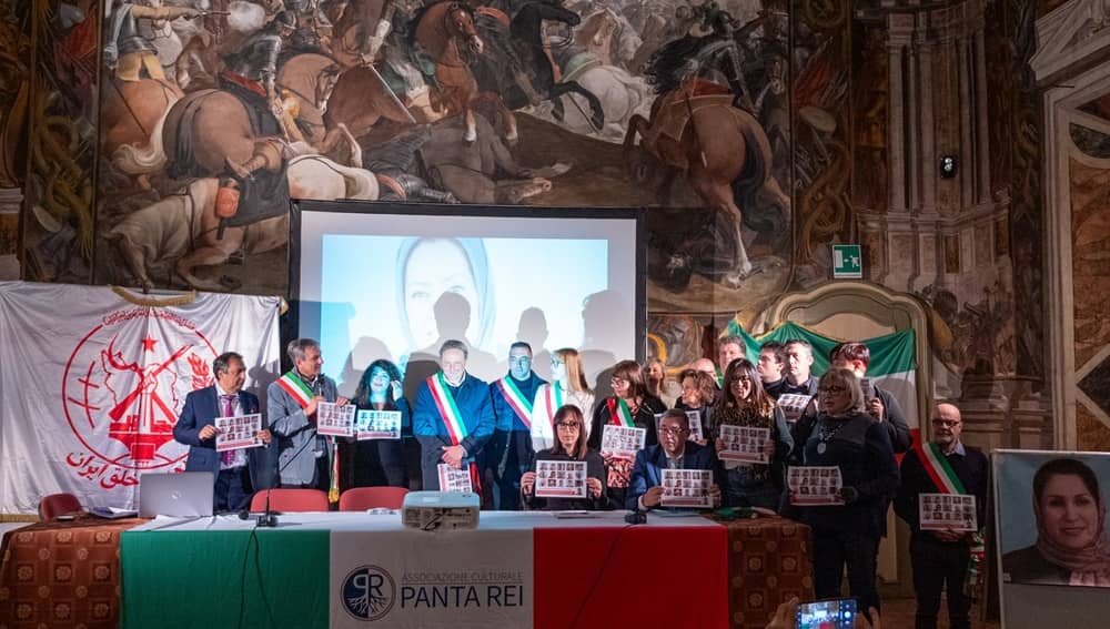 NCRI supporters, Italian local officials and civil society representatives gather in Savigliano’s historic Taffini Hall on 5 December 2025, holding images of Iranian political prisoners