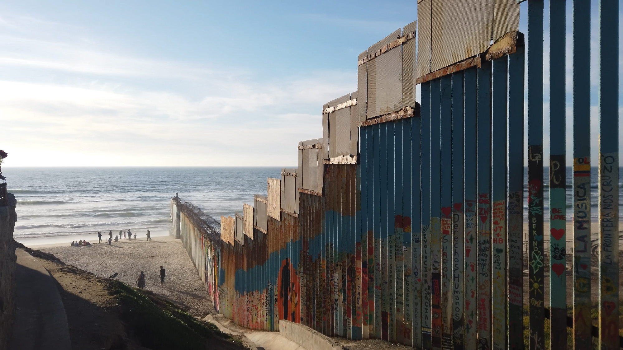 border wall extends down beach into ocean