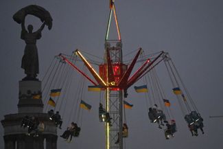 Visitors ride an attraction decorated with Ukrainian flags at a Christmas fair held at the Expocenter of Ukraine in Kyiv. December 21, 2025.