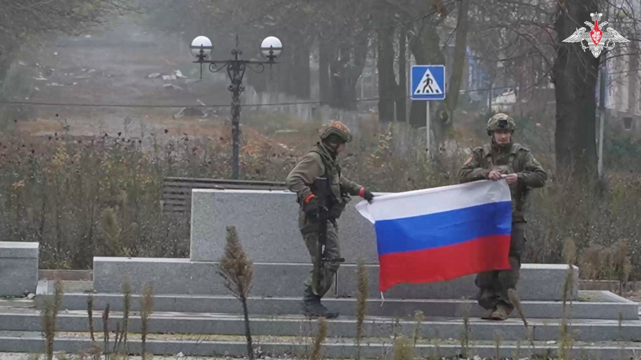 Soldiers hold a Russian flag in Pokrovsk near a signboard in the Donetsk region