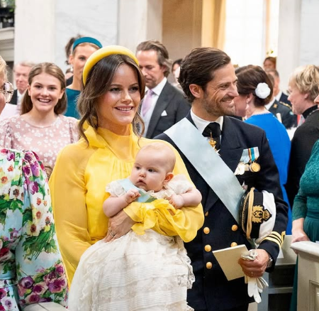 Princess Sofia carries her daughter, Princess Ines, through the royal chapel at the baby's christening with future queen, Princess Estelle, smiling at them. The Swedish Royal Family celebrates Princess Ines's christening