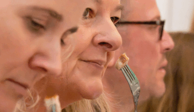 Three people sampling different sausages at Oktoberfest