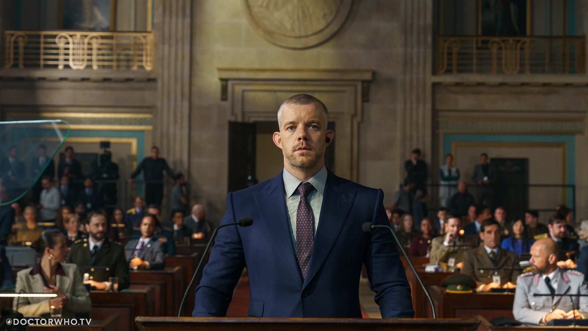 Promotional material for "The War Between the Land and the Sea" showing Russell Tovey as Barclay, standing in court wearing a blue suit.