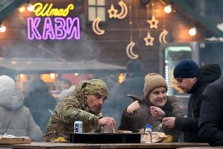 People eat street food at the Christmas fair at the Expocenter of Ukraine in Kyiv. December 21, 2025.