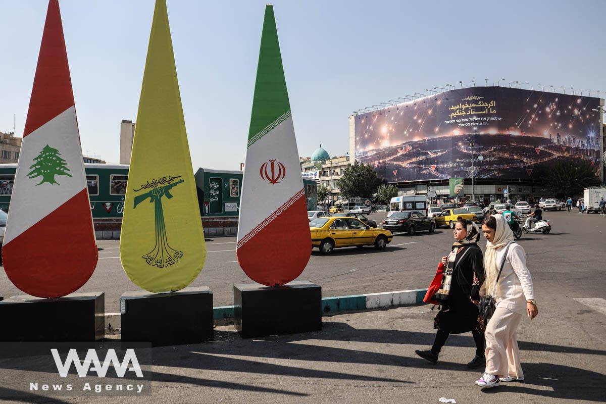 People walk past a banner with a picture of the late Lebanon's Hezbollah leader Hassan Nasrallah, in a street