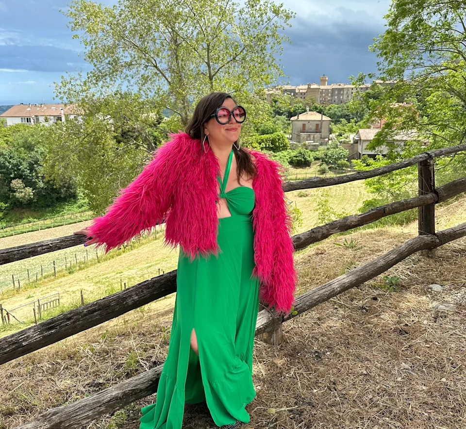 Woman in pink coat and green dress in Italian countryside