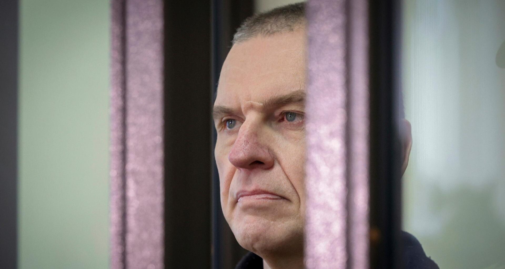 Der inhaftierte belarussische Journalist Andrzej Poczobut im Seitenporträt hinter einem Gitter.