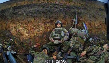 Drone POV: Last remaining Russian infantry sits on a pile of corpses of his dead comrades, looking at the approaching FPV.