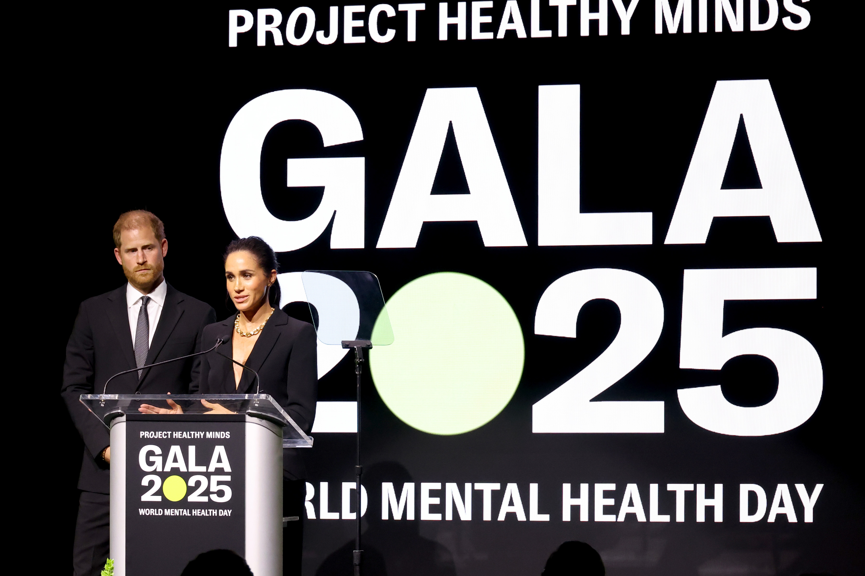 Prince Harry and Meghan Markle speaking at a podium during World Mental Health Day gala