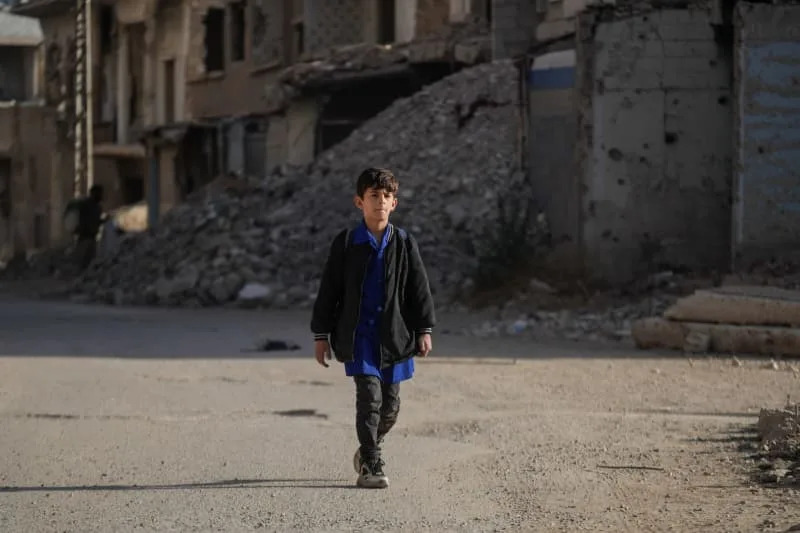 A Syrian boy walks past destroyed buildings in Harasta. Syria has suffered immense destruction due to the ongoing conflict, leading to widespread poverty, infrastructure damage, and a collapse of services. Moawia Atrash/dpa