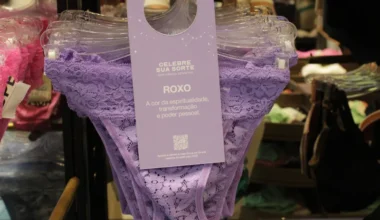 Calcinha roxa de renda exposta em um suporte com tag informativa sobre espiritualidade e poder pessoal.