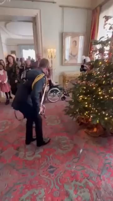 Camilla's new equerry hangs a Christmas tree ornament with his sword for at annual tea party for terminally ill children at Clarence House