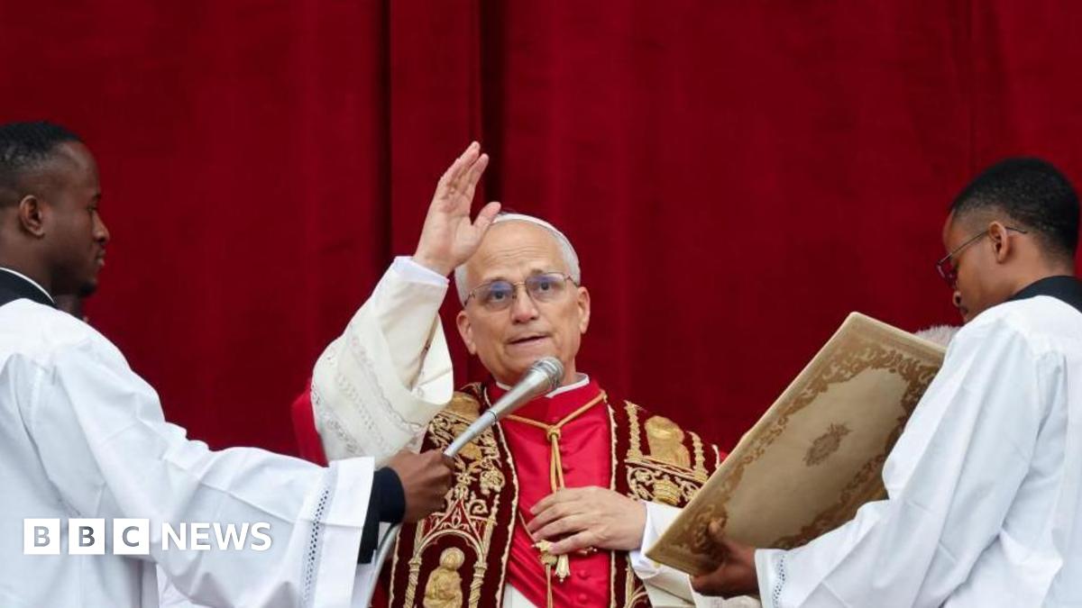 Pope Leo speaking into a microphone during his Christmas address and holding his hand in the air