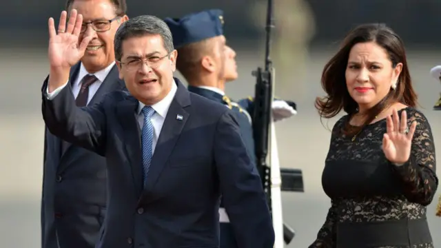 Juan Orlando Hernández saluda con su mano derecha mientras que con la izquierda toma de la mano a su esposa, Ana García 