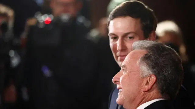 Two men appear in front of cameras