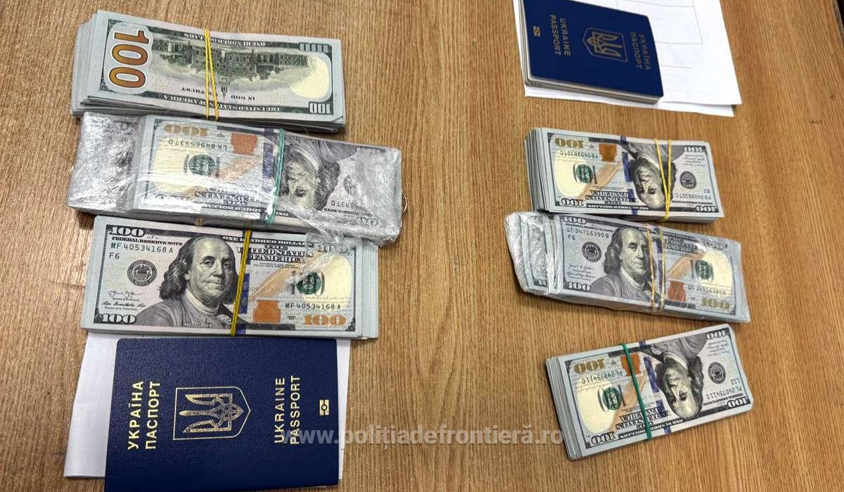 60.000 de dolari în hârtii de câte 100 de dolari, așezate pe o masă din lemn maro, lângă două pașapoarte de Ucraina