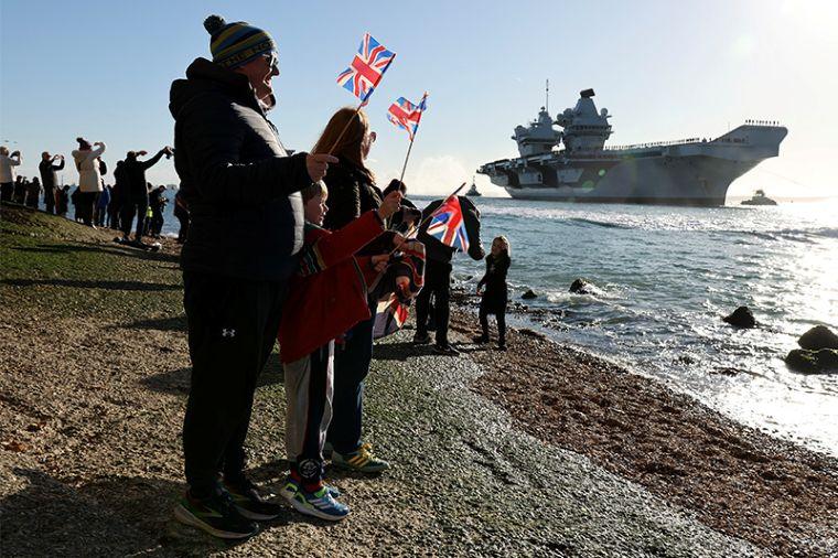 Britons waving flags at an aircraft carrier