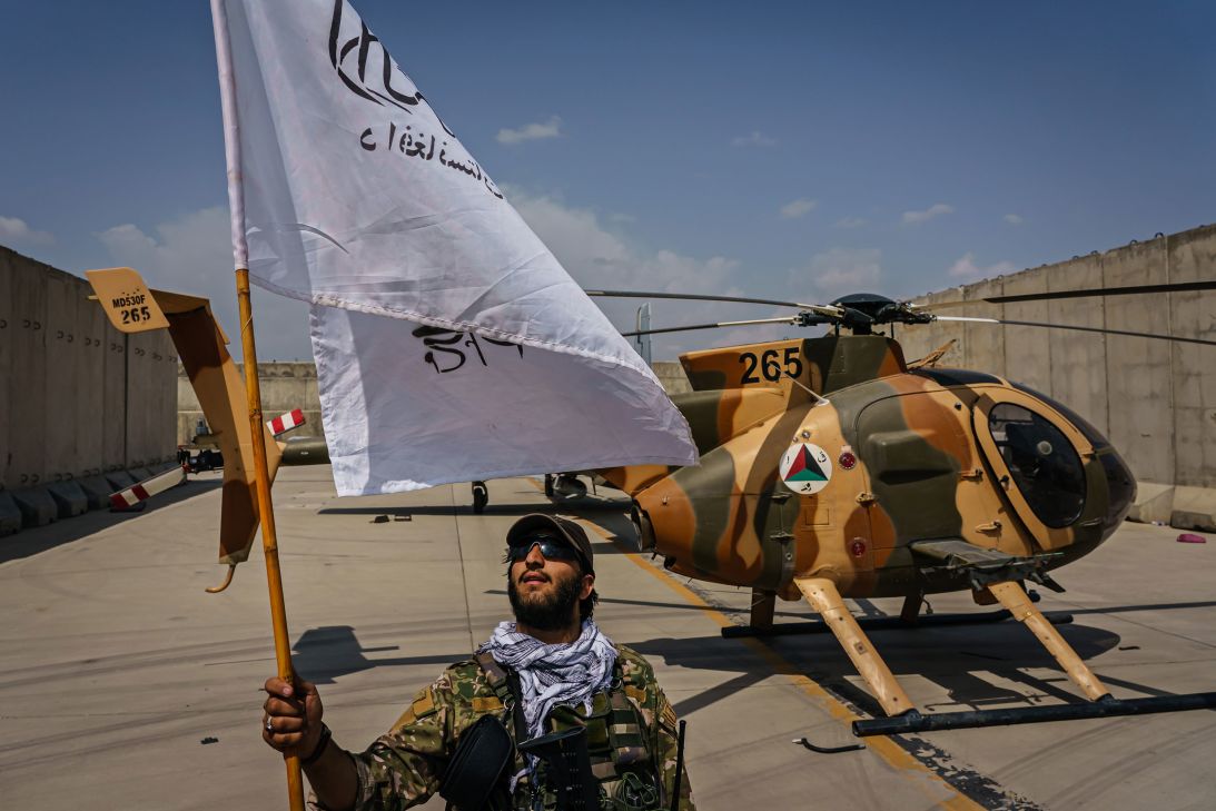 A Taliban fighter raises the movement's flag while touring military assets left behind on the military airbase side of Hamid Karzai International Airport in Kabul, Afghanistan, in the wake of the American forces' withdrawal from the country, on August 31, 2021.