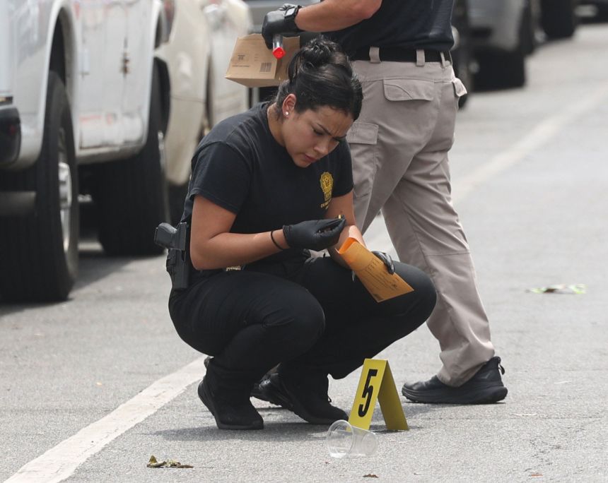 An NYPD crime scene investigator collects a shell casing where a shooting occurred in the Crown Heights neighborhood of Brooklyn, New York, on August 17.