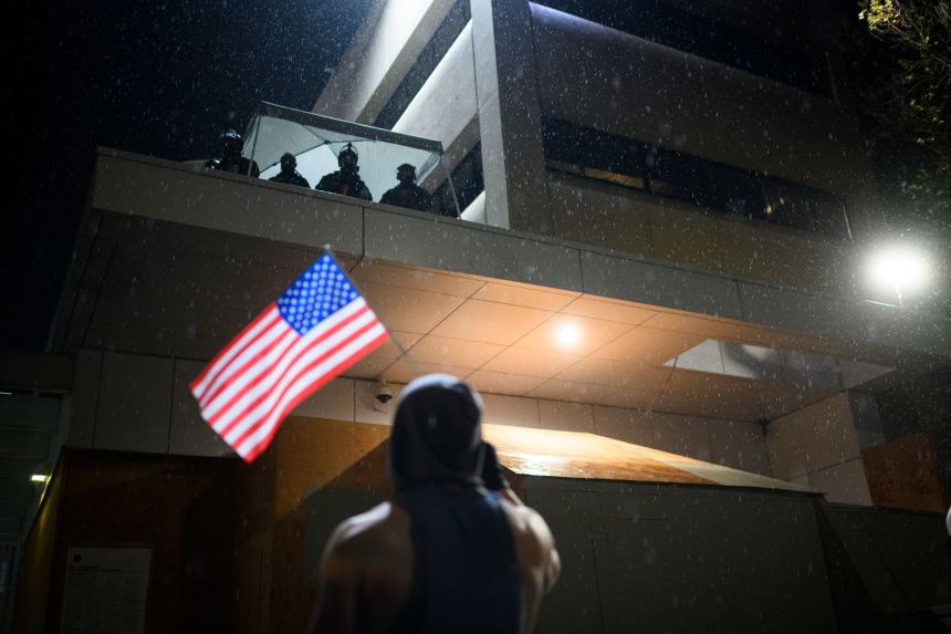 An anti-ICE protester holds an American flag near the US Immigration and Customs Enforcement building in Portland, Oregon, on October 18.