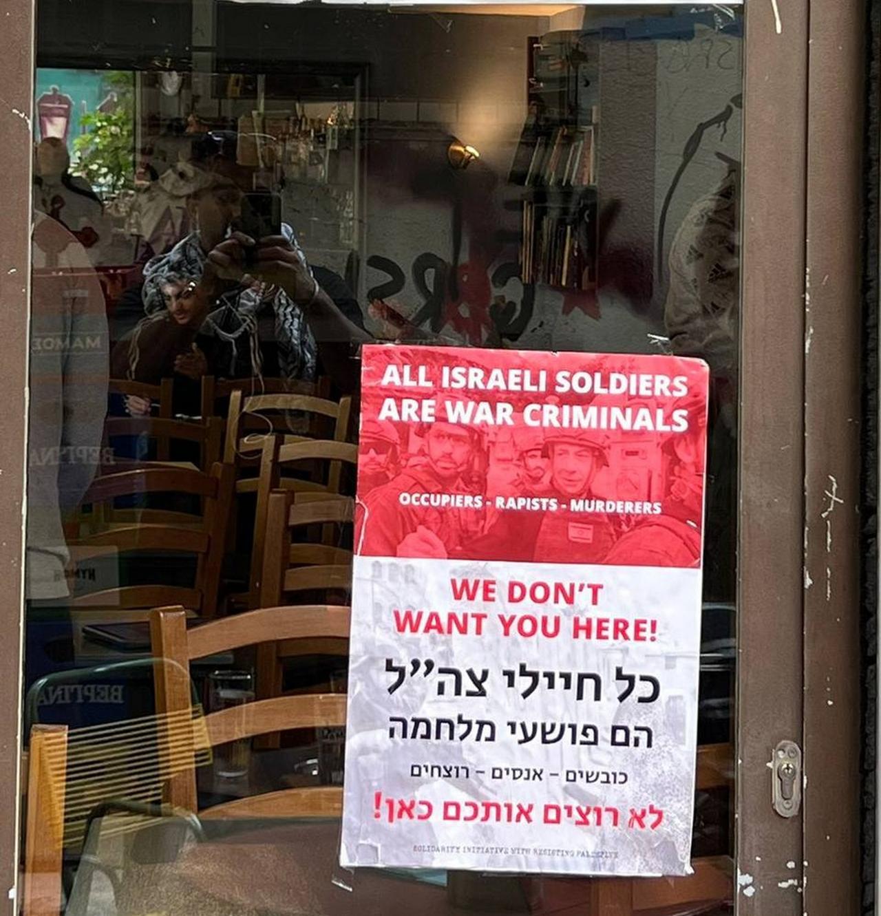 A protest poster displayed on the window of a café criticizing the Israeli military, Athens, April 28, 2025. (Photo via Instagram/@translating_falasteen)