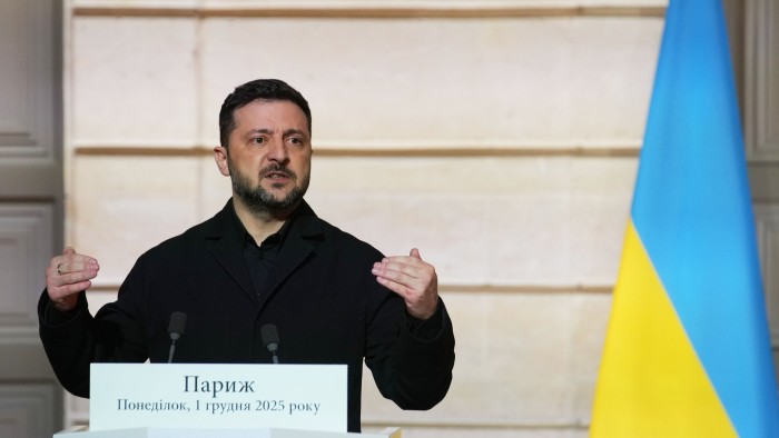 Volodymyr Zelenskyy delivers a speech at a podium with a Ukrainian flag visible in the background.